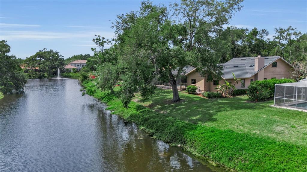 An aerial view shows a house with a screened pool enclosure beside a canal — 1732 PINE HARRIER CIRCLE, SARASOTA, FL