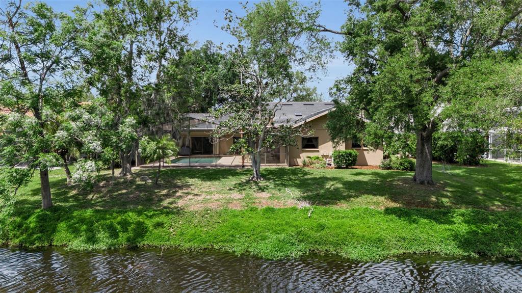 A single-story house with a screened pool sits on a grassy lot beside a canal — 1732 PINE HARRIER CIRCLE, SARASOTA, FL