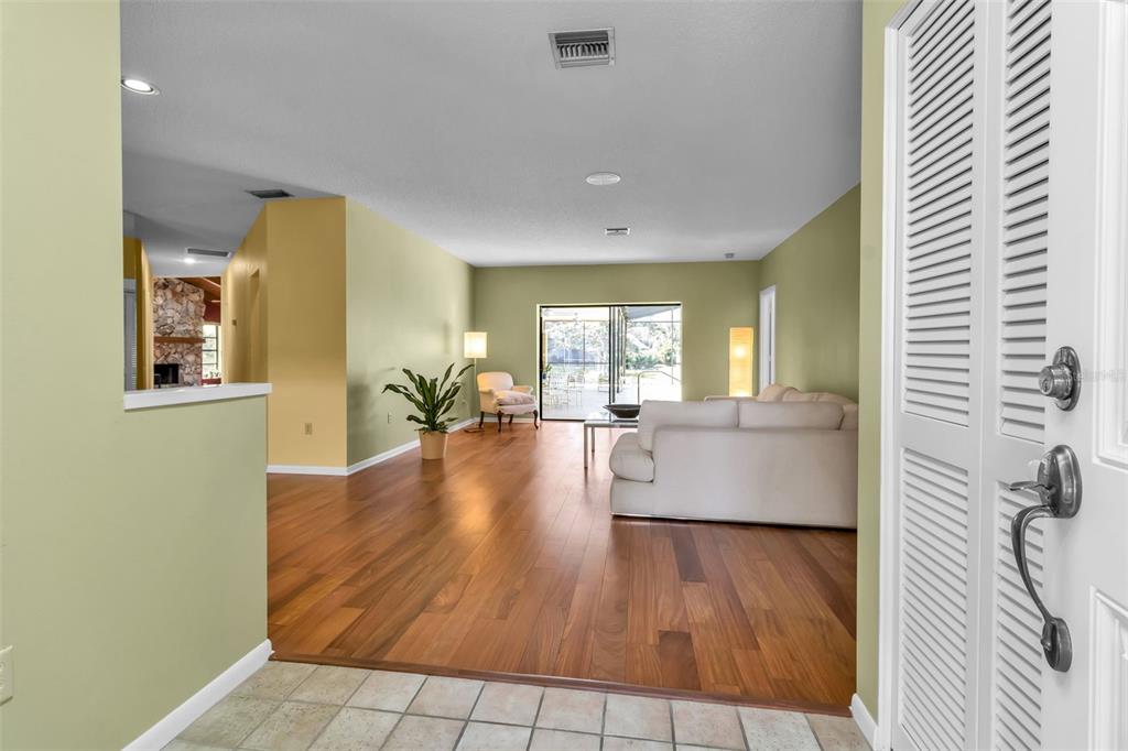 A view from a tiled entryway into a living room with hardwood floors and sliding doors — 1732 PINE HARRIER CIRCLE, SARASOTA, FL