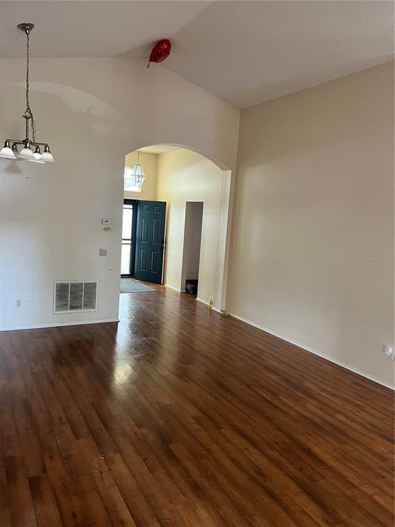 An interior view of a living area with hardwood floors, vaulted ceilings, and an arched entryway — 801 KAMCHATKA COURT, APOPKA, FL