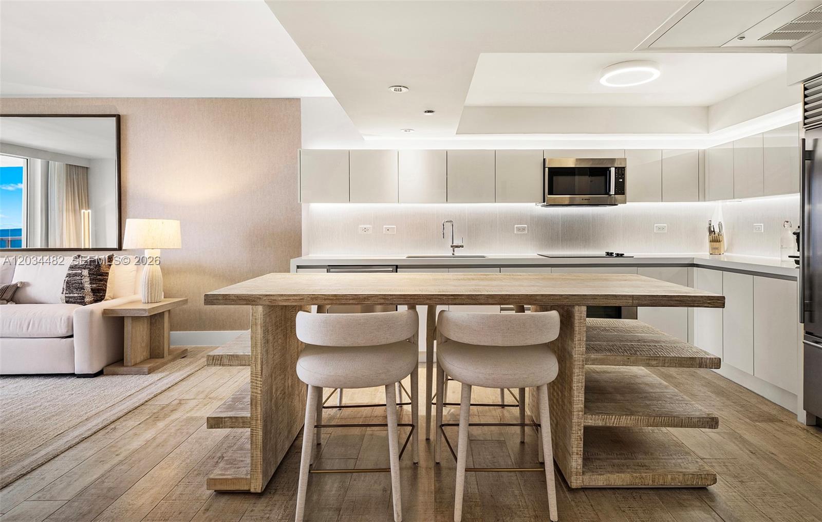 A modern kitchen features light wood cabinetry, a central island with seating, and integrated appliances — 102 24th St # 1112, Miami Beach FL 33139, MIAMI BEACH, FL
