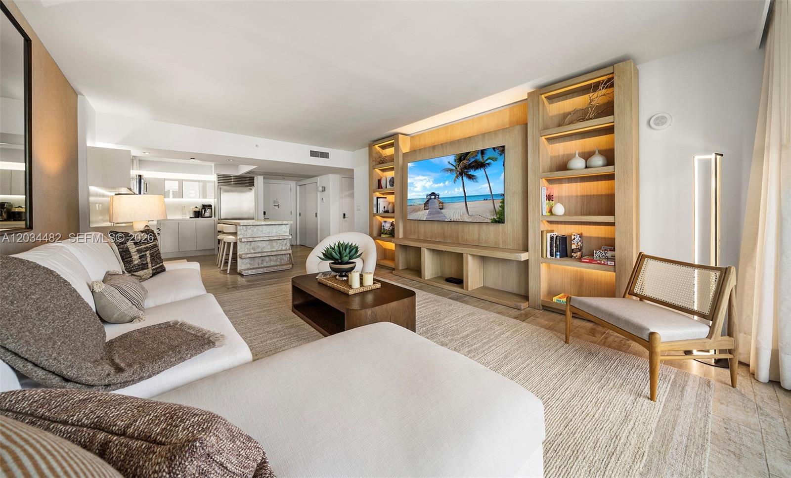 A modern living room features a large sectional sofa, a wooden media wall, and shelving — 102 24th St # 1112, Miami Beach FL 33139, MIAMI BEACH, FL