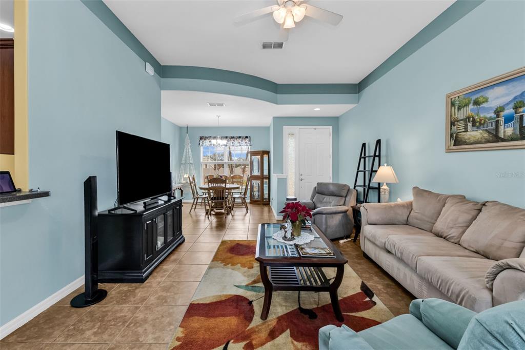 A living room with light blue walls, tile flooring, a beige sofa, and a dining area — 1955 YORKTOWN TRAIL, PUNTA GORDA, FL