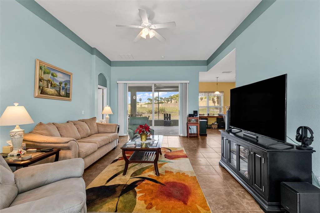 A living room features a beige sofa, a floral rug, and a television on a console — 1955 YORKTOWN TRAIL, PUNTA GORDA, FL