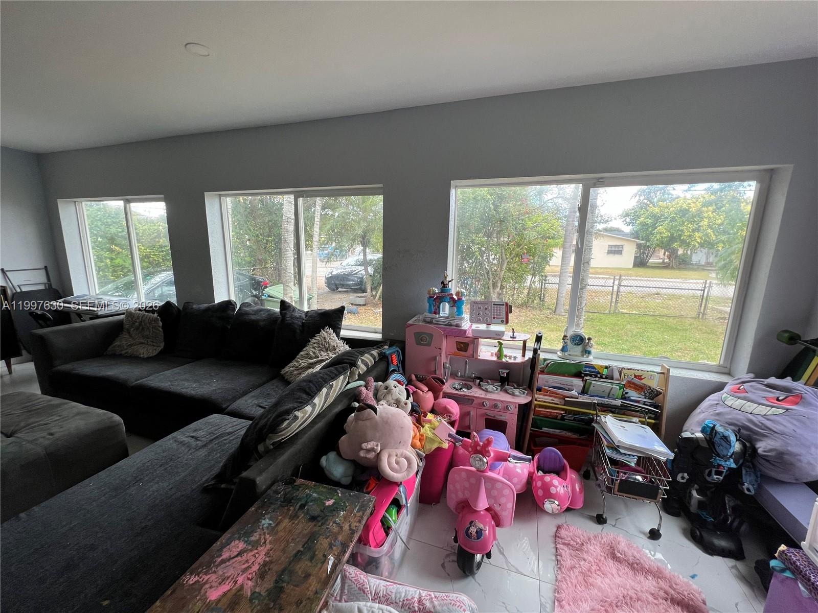 A living room features a large sectional sofa, multiple windows, and a play area — 450 NW 4th Ave, Homestead FL 33030, HOMESTEAD, FL