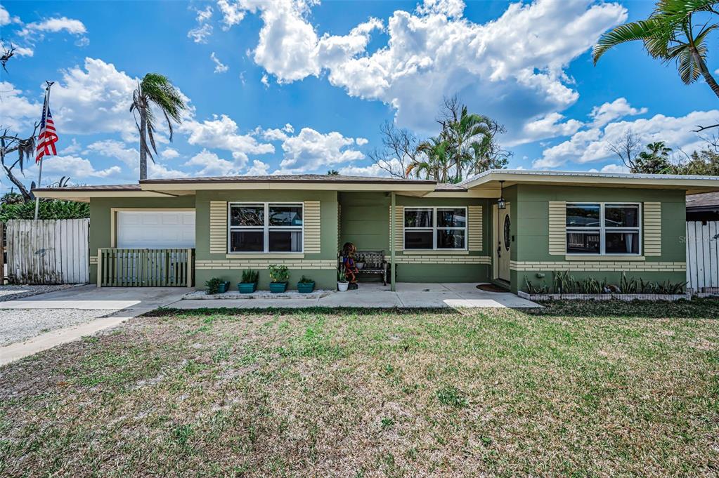 A single-story green house with a front porch, garage, and an American flag — 5146 MALLETT DRIVE, PORT RICHEY, FL