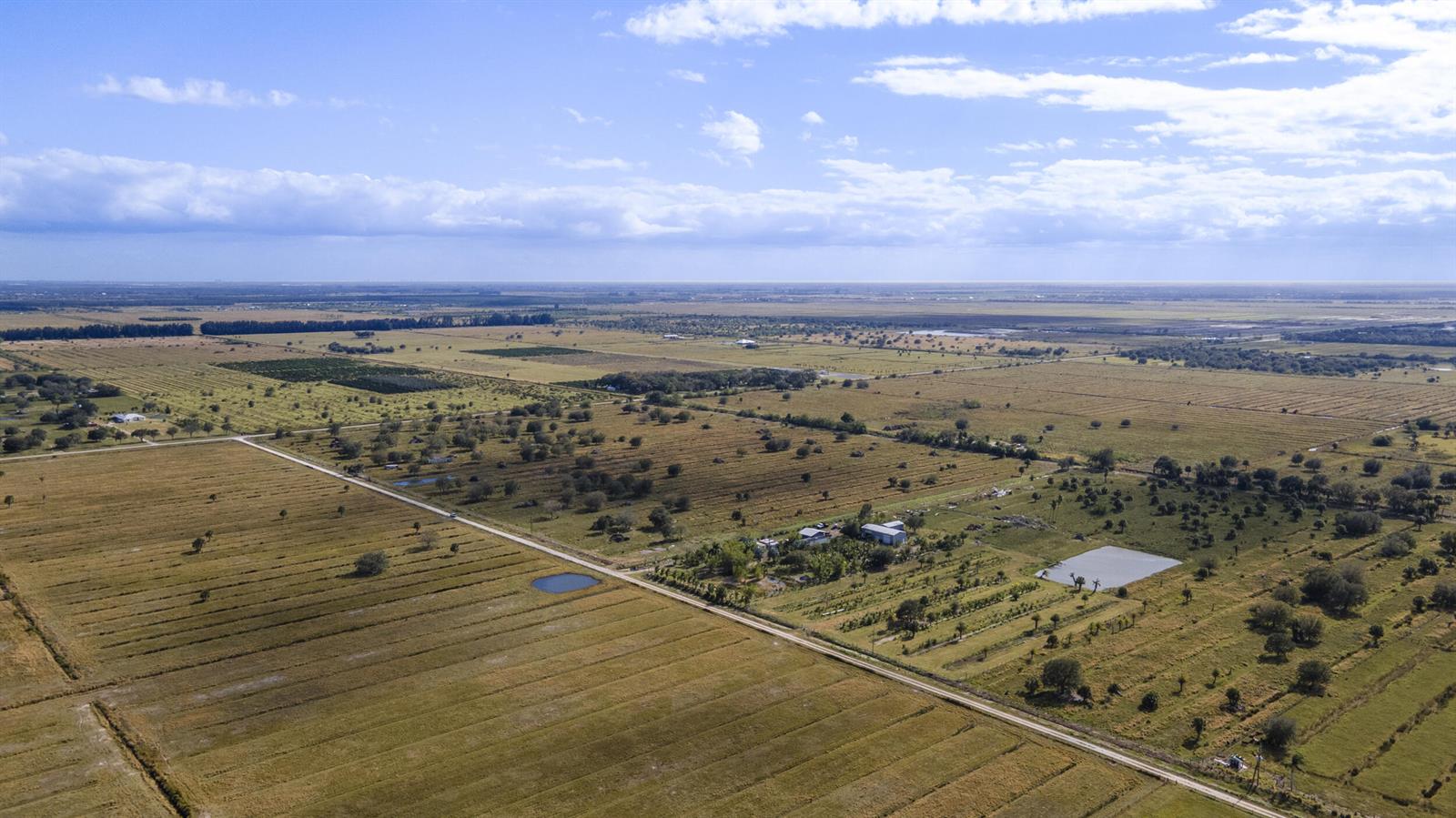 An aerial view shows a rural property with a house, outbuildings, and a small pond — 2321 Sneed Road, Fort Pierce FL 34945, FORT PIERCE, FL