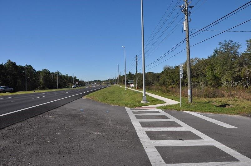 A paved road runs alongside a grassy shoulder with a crosswalk and utility poles — 11507 CORTEZ BOULEVARD UNIT 102, BROOKSVILLE, FL