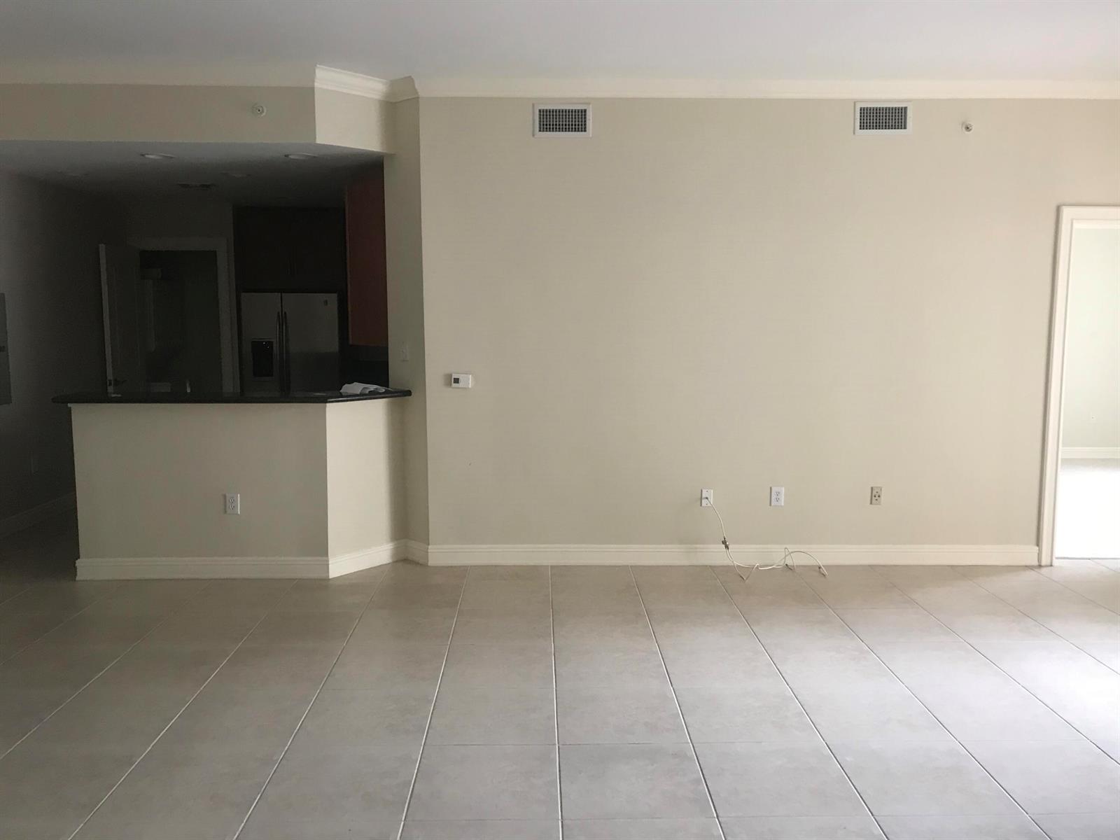 A spacious living area features beige walls, tile flooring, and an open kitchen counter — 16102 Emerald Estates Drive # 212, Weston FL 33331, WESTON, FL