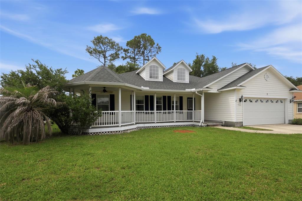 A single-story house with white siding, a wrap-around porch, and an attached two-car garage — 3 EASTGATE LANE, PALM COAST, FL