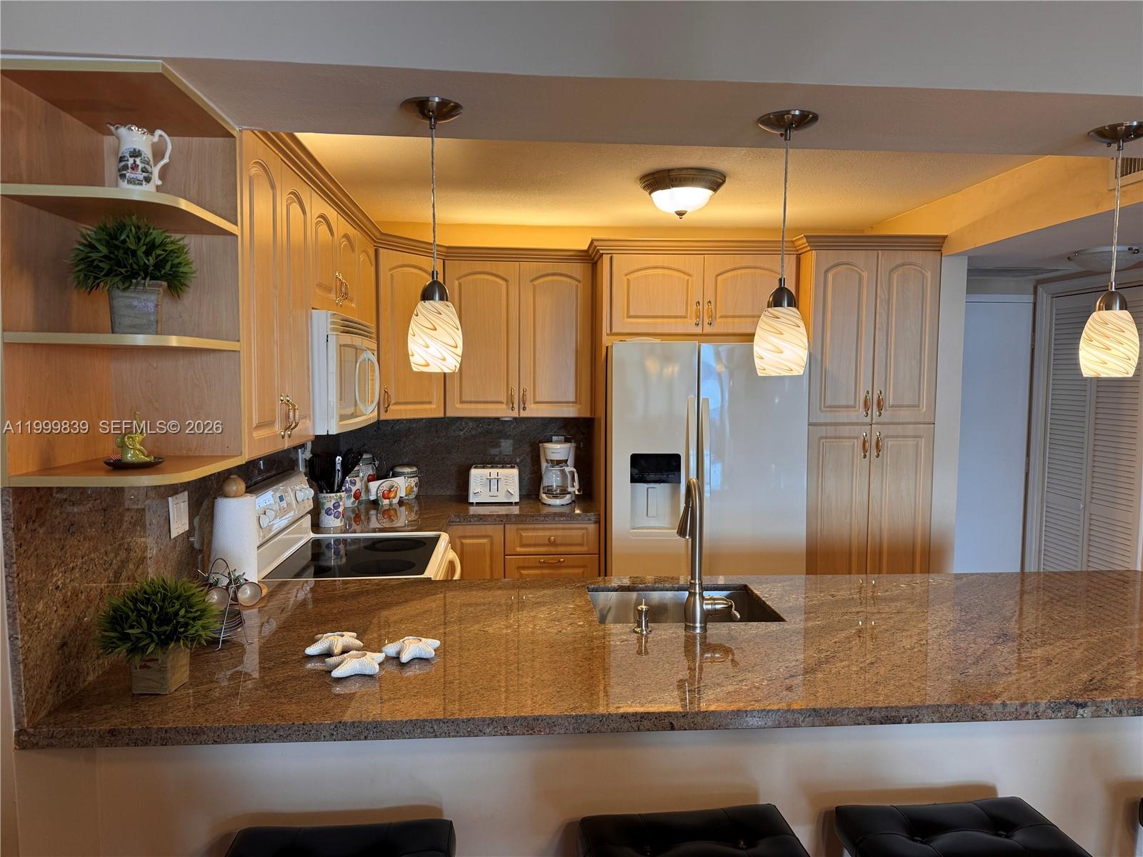 A kitchen features light wood cabinets, granite countertops, a breakfast bar, and pendant lighting — 3725 S Ocean Dr # 421, Hollywood FL 33019, HOLLYWOOD, FL