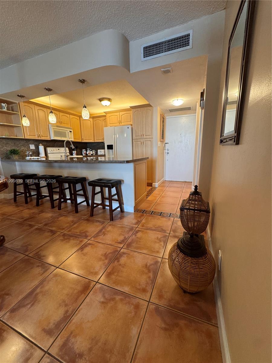 A kitchen features light wood cabinets, a breakfast bar with stools, and tiled flooring — 3725 S Ocean Dr # 421, Hollywood FL 33019, HOLLYWOOD, FL