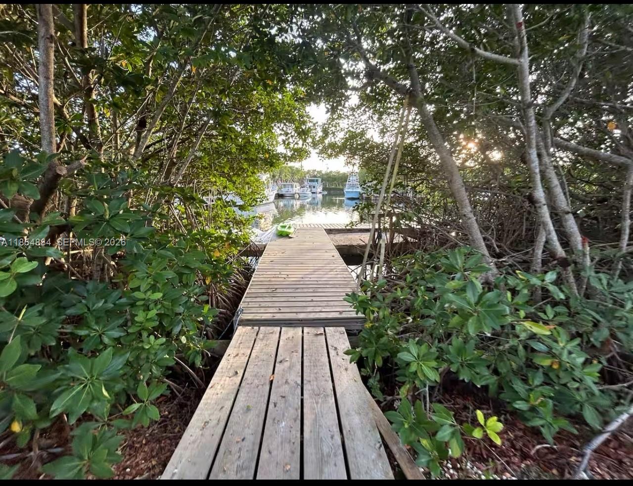 A wooden dock leads through dense mangrove trees toward a small marina with several boats — 350 Hazel St, Key Largo FL 33037, KEY LARGO, FL