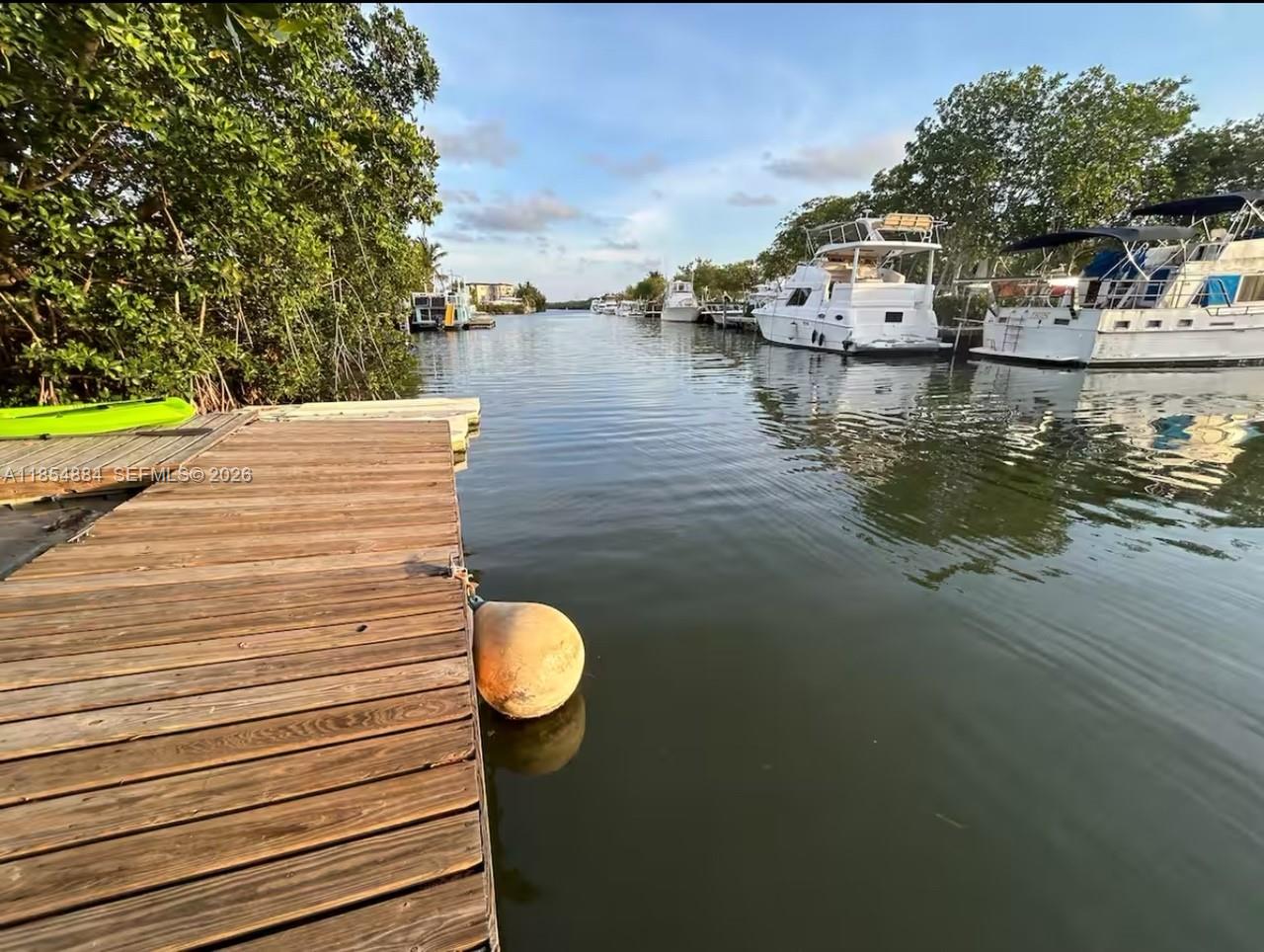A wooden dock overlooks a canal lined with moored boats and lush green trees — 350 Hazel St, Key Largo FL 33037, KEY LARGO, FL