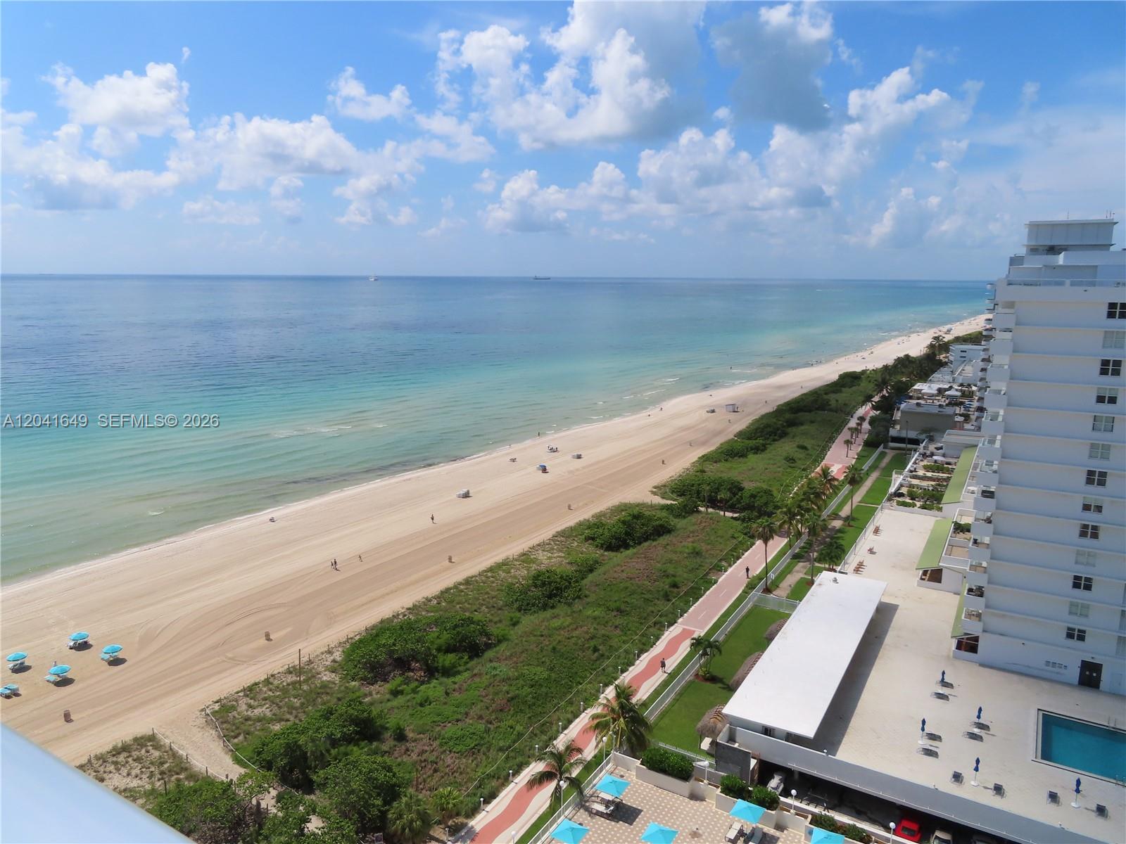An elevated view of a sandy beach, ocean, and a high-rise building — 5701 Collins Ave # 619, Miami Beach FL 33140, MIAMI BEACH, FL