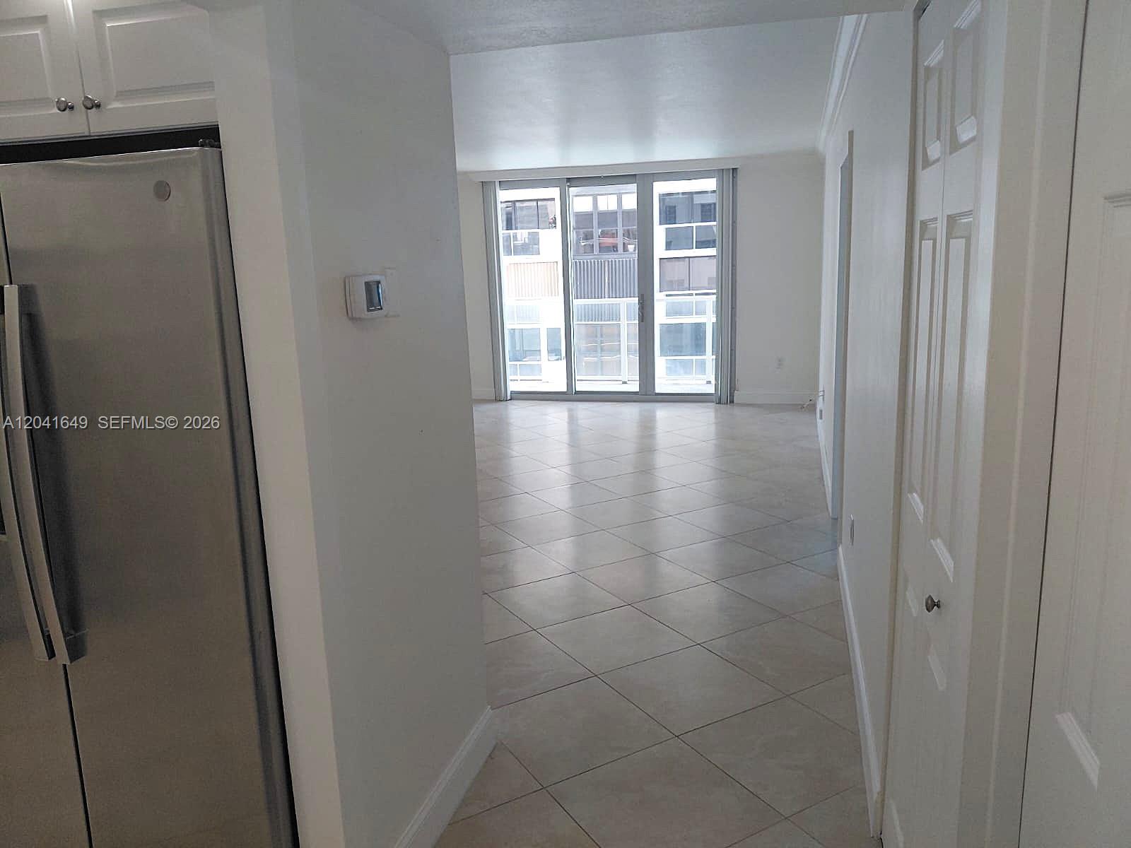 A view from a kitchen hallway looking toward a living area with sliding glass doors — 5701 Collins Ave # 619, Miami Beach FL 33140, MIAMI BEACH, FL
