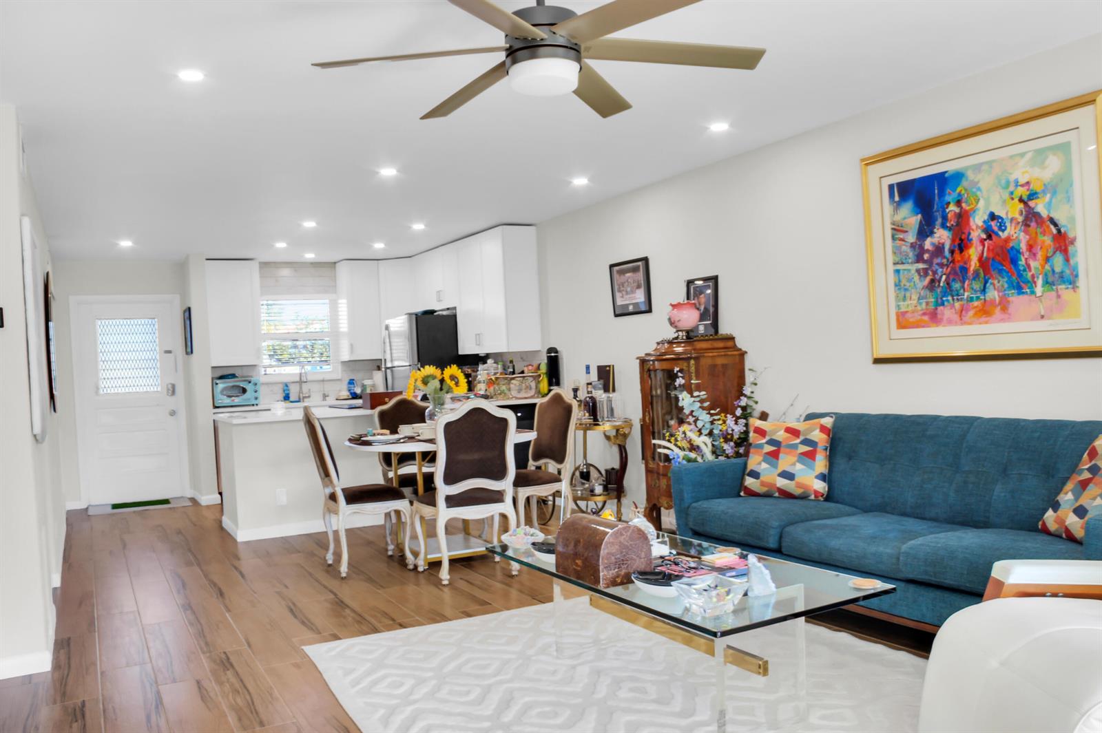 An open-concept living and dining area features a blue sofa, glass coffee table, and kitchen — 2202 NE 36th Street # 15, Lighthouse Point FL 33064, LIGHTHOUSE POINT, FL