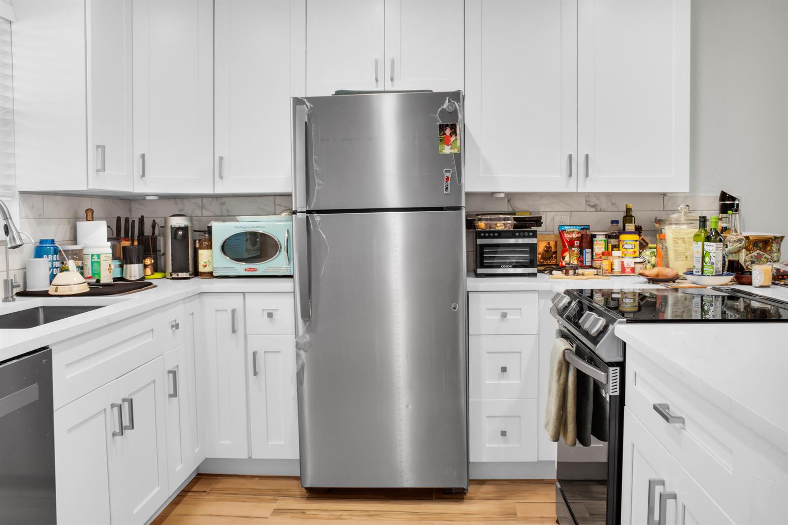 A kitchen features white cabinets, stainless steel appliances, and wood-look flooring — 2202 NE 36th Street # 15, Lighthouse Point FL 33064, LIGHTHOUSE POINT, FL