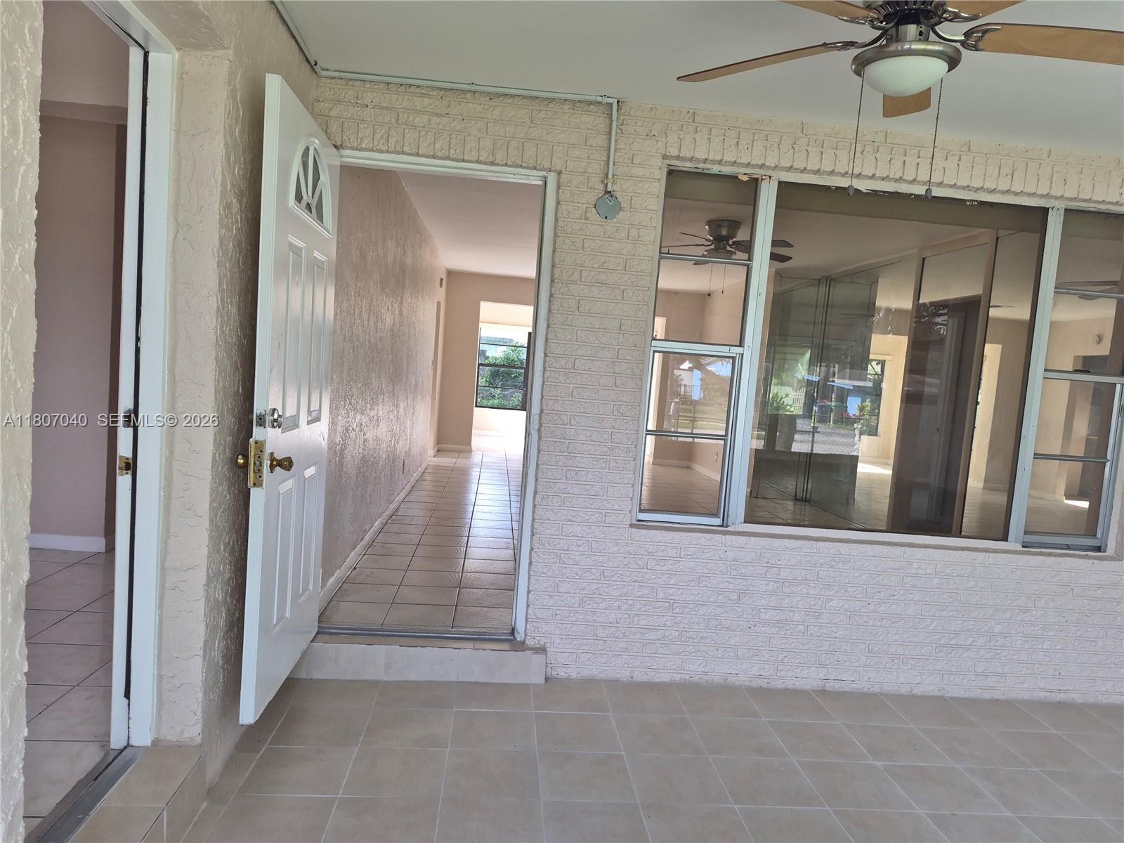 A sunroom with beige tile flooring, large windows, and a view of a backyard — 3161 NW 5th St, Lauderhill FL 33311, LAUDERHILL, FL
