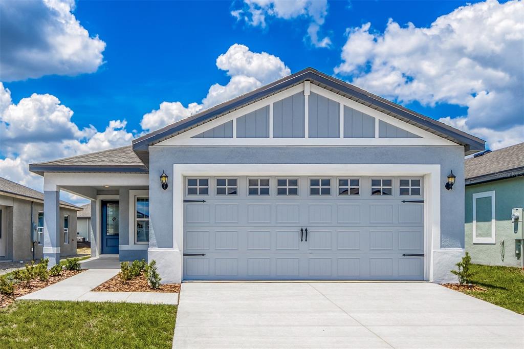 A light blue single-story house features a two-car garage and a covered front entryway — 3715 BERGAMOT STREET, LAKE ALFRED, FL