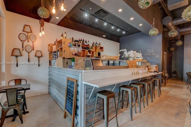 A restaurant interior features a bar with metal stools, wooden shelving, and tennis racket wall decor — S University Dr, Plantation FL 33324, PLANTATION, FL