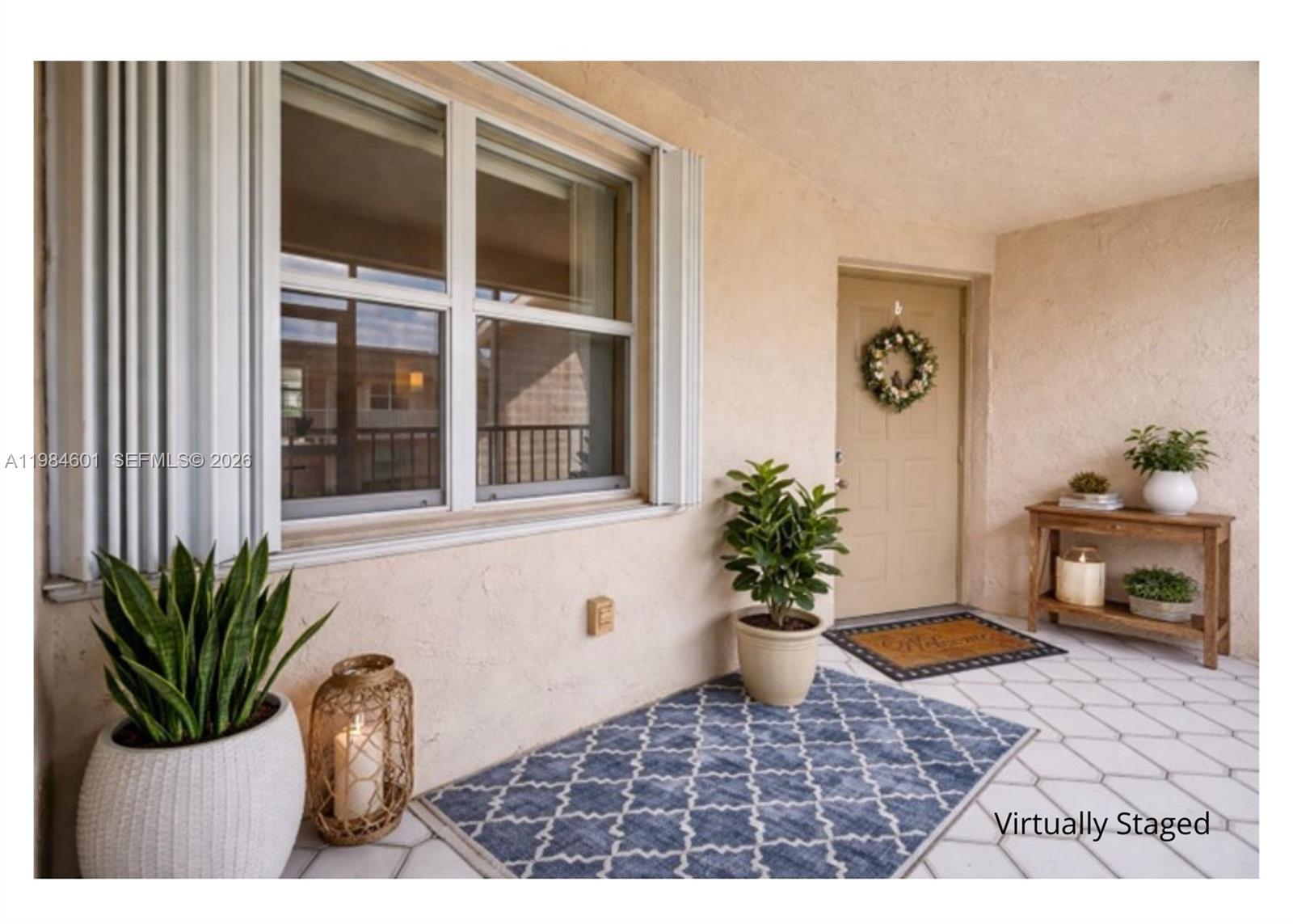 A covered patio features a tiled floor, a front door with a wreath, and potted plants — 889 Hamilton Dr # 889L, Homestead FL 33034, HOMESTEAD, FL