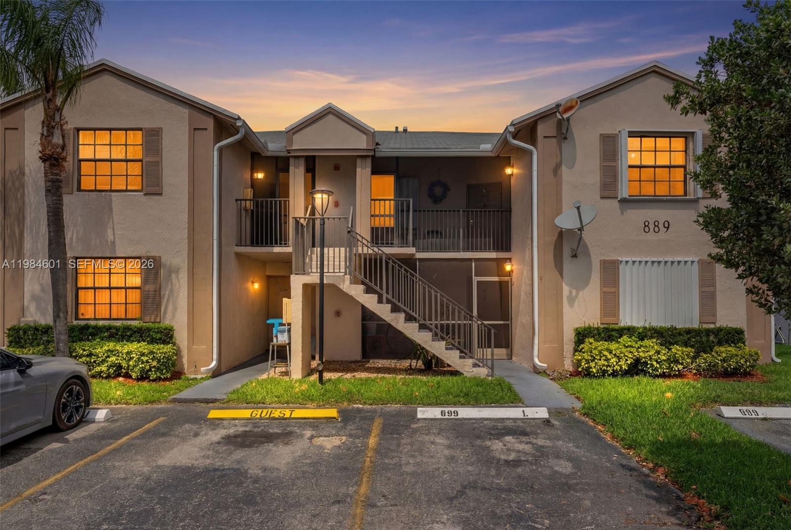 A two-story apartment building exterior features a central staircase, parking spaces, and exterior lighting — 889 Hamilton Dr # 889L, Homestead FL 33034, HOMESTEAD, FL