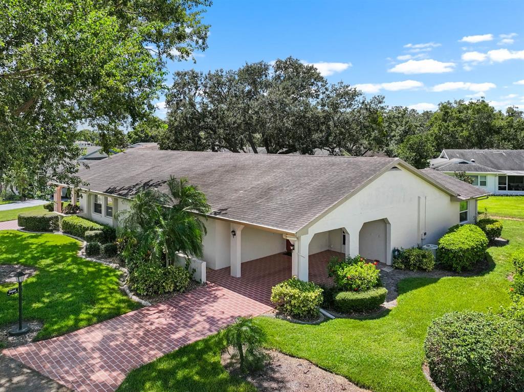 An exterior view of a single-story house with a brick driveway and a covered carport — 2109 HARLESTON PLACE UNIT 2109, SUN CITY CENTER, FL