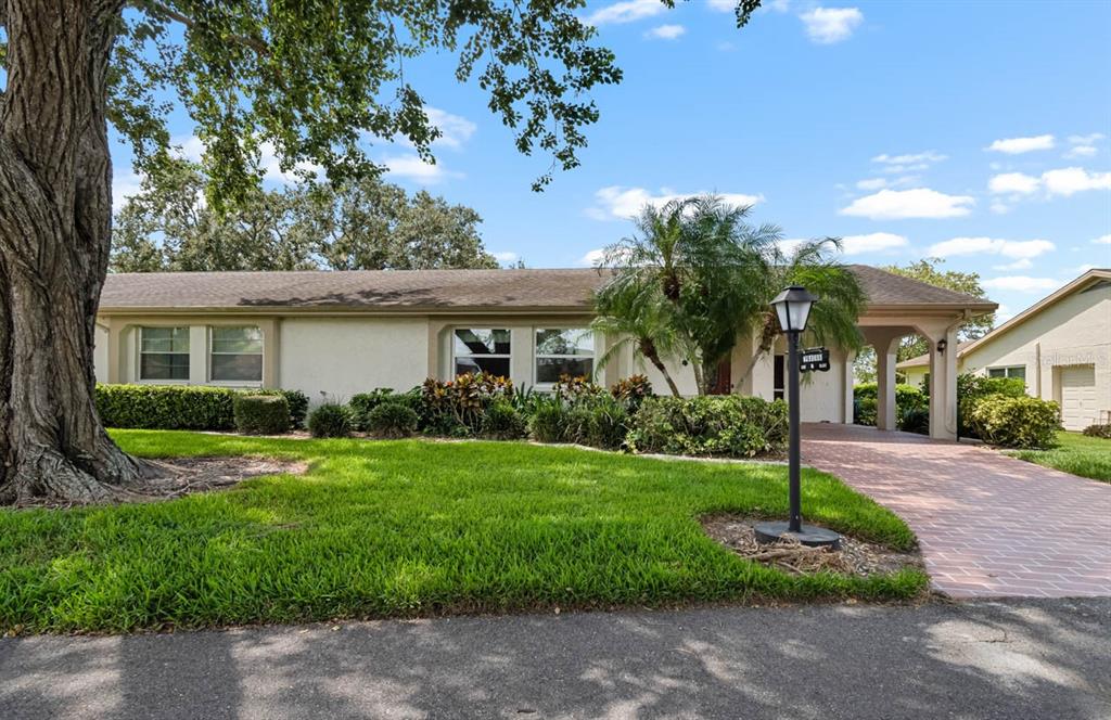 A single-story house with a brick driveway, a large tree, and a front lawn — 2109 HARLESTON PLACE UNIT 2109, SUN CITY CENTER, FL