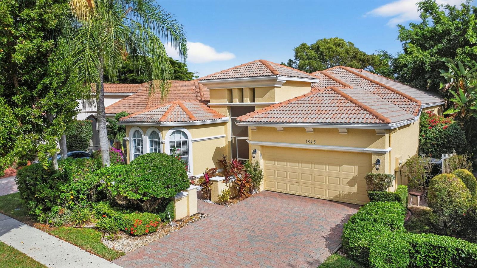 An aerial view of a yellow single-story house with a tile roof and brick driveway — 1848 Via Castello, Wellington FL 33411, WELLINGTON, FL
