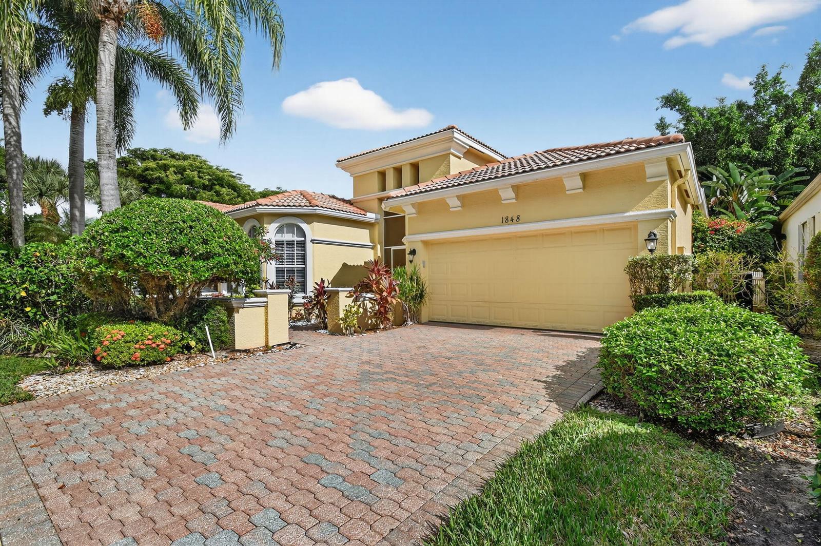 A yellow single-story house with a tiled roof and a brick paver driveway — 1848 Via Castello, Wellington FL 33411, WELLINGTON, FL