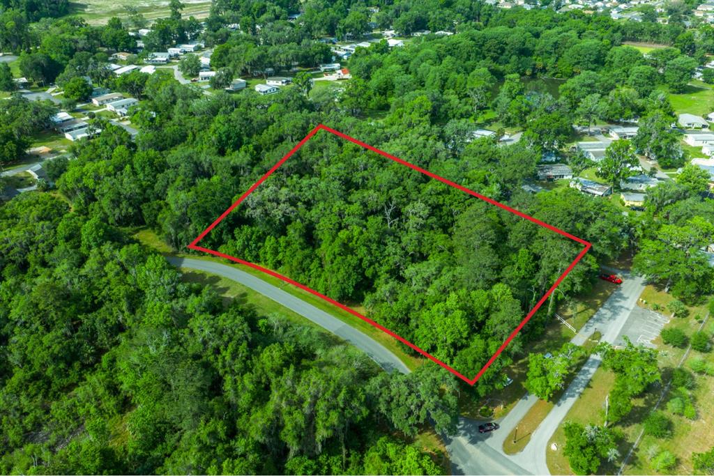 An aerial view shows a rectangular plot of land outlined in red amidst dense trees — TBD NW 45TH TERRACE, OCALA, FL