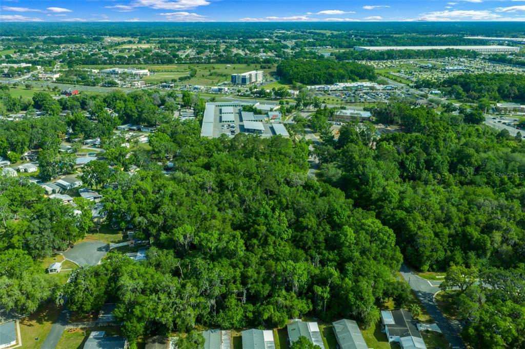 An aerial view shows a wooded lot surrounded by residential neighborhoods and commercial buildings — TBD NW 45TH TERRACE, OCALA, FL