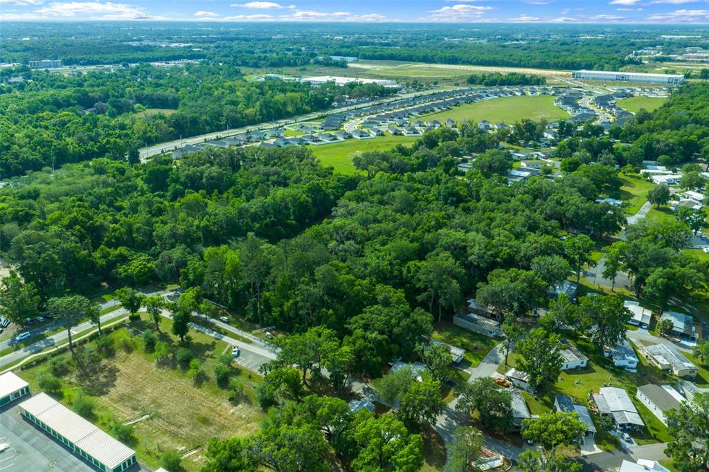 An aerial view shows a residential neighborhood surrounded by dense trees and open green space — TBD NW 45TH TERRACE, OCALA, FL