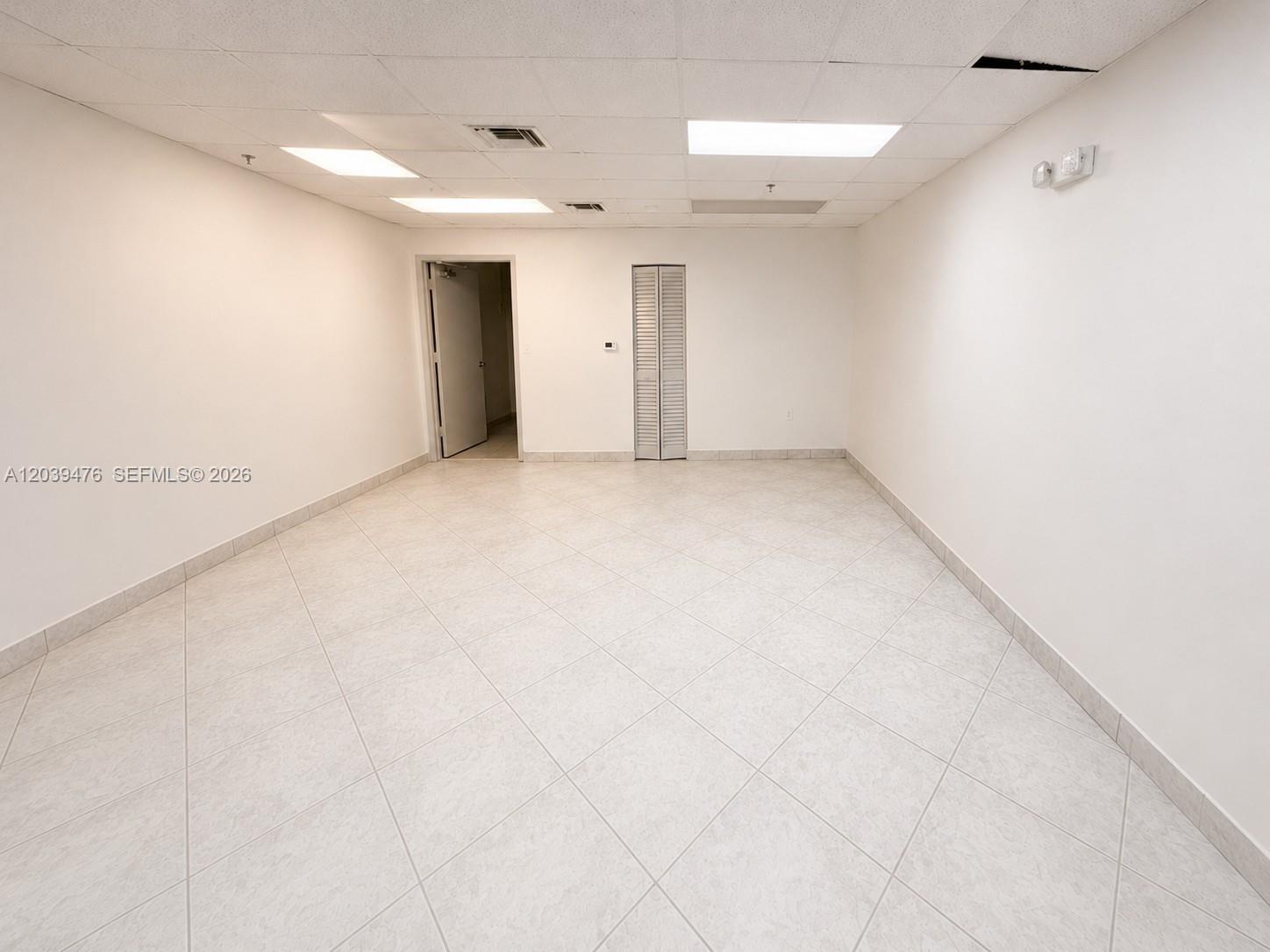 An empty office room features white walls, a tiled floor, and a drop ceiling — 8554 NW 61st St, Miami FL 33166, MIAMI, FL