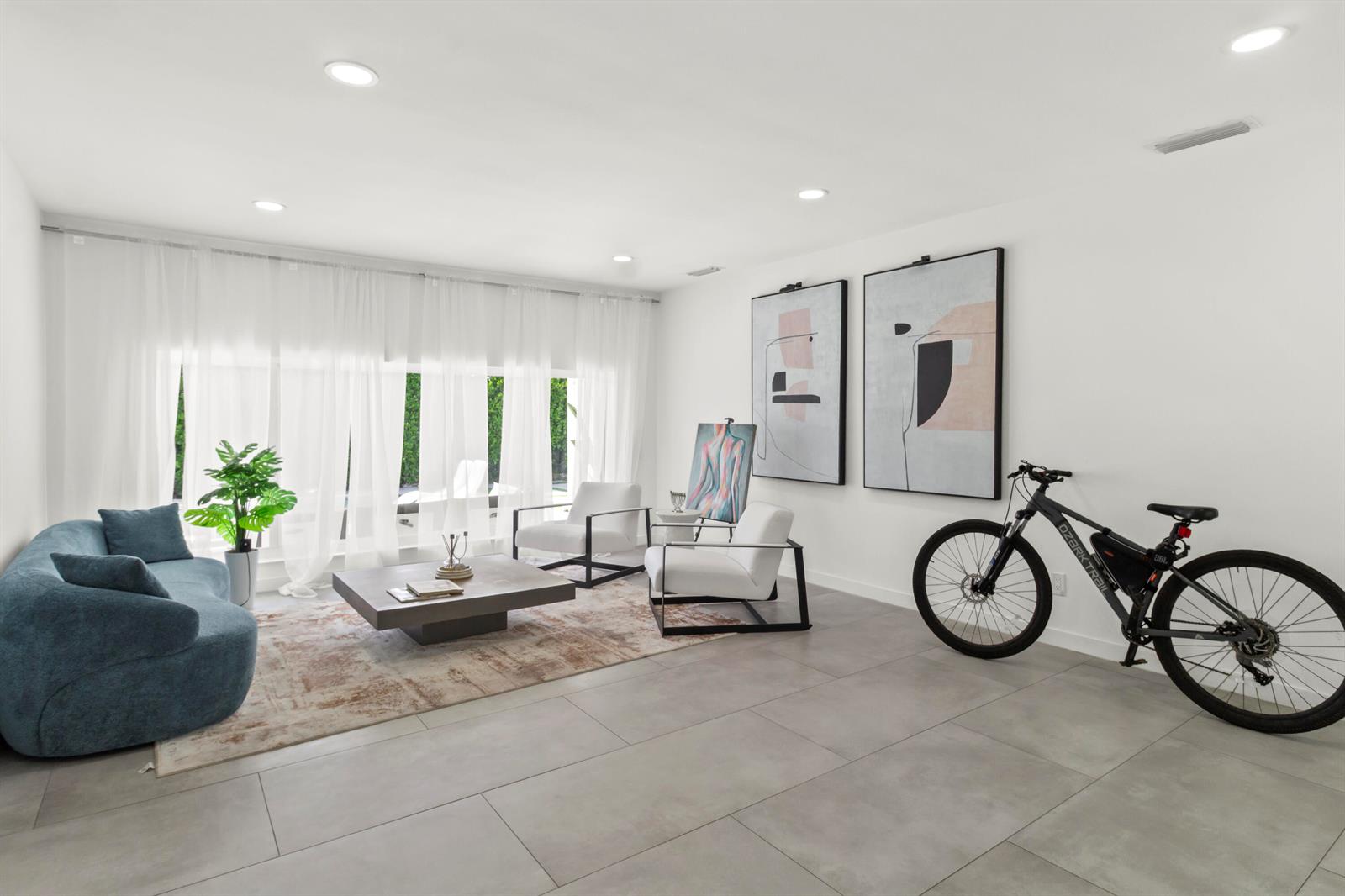 A modern living room features a blue sofa, two white chairs, and a bicycle — 21303 NE 18th Place, Miami FL 33179, MIAMI, FL