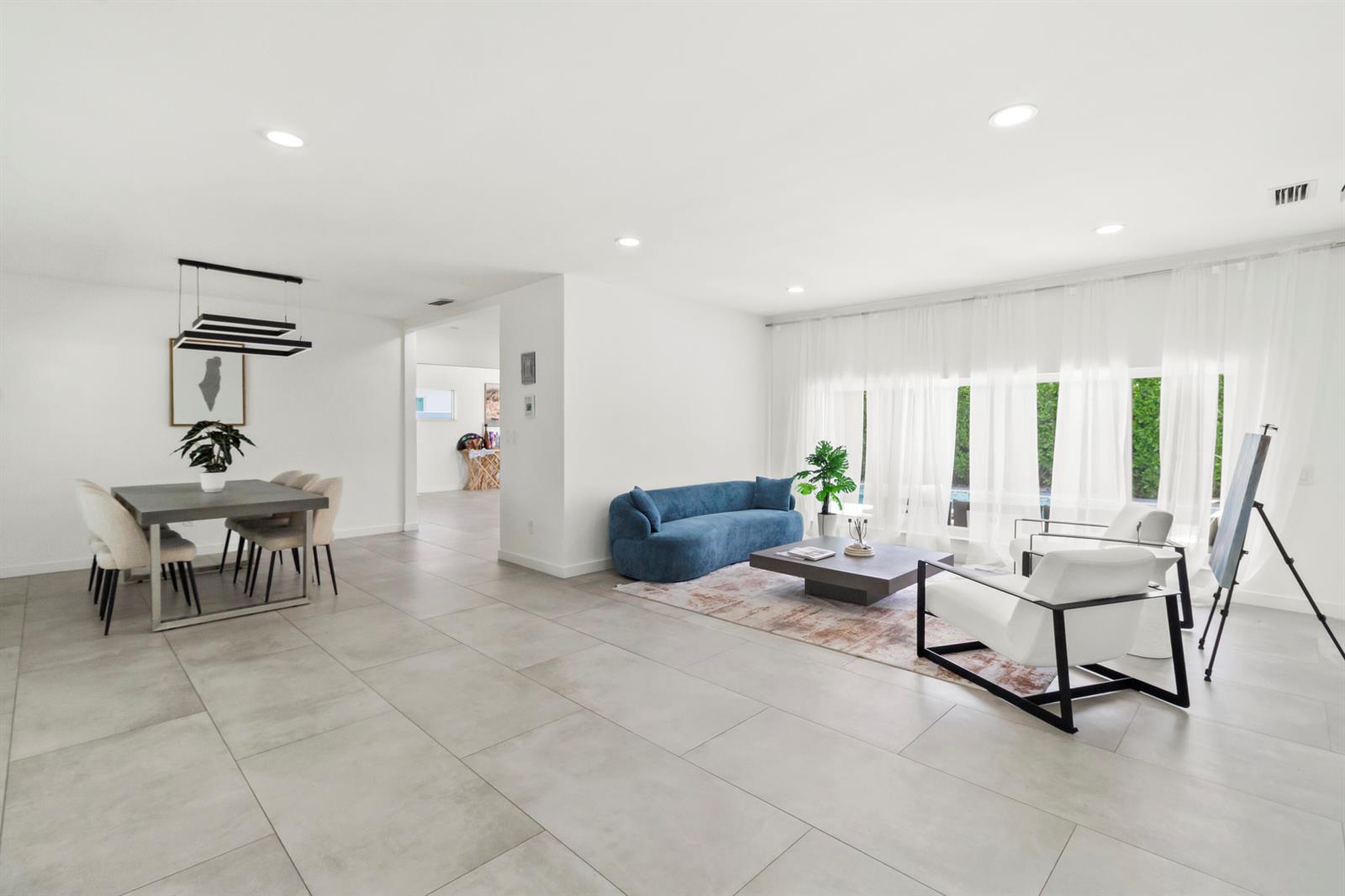 A modern open-concept living and dining area with large gray floor tiles and white walls — 21303 NE 18th Place, Miami FL 33179, MIAMI, FL