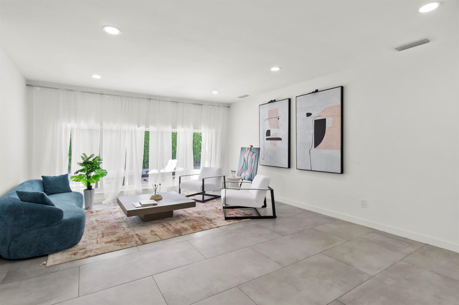 A modern living room features a blue sofa, two white chairs, and large abstract art — 21303 NE 18th Place, Miami FL 33179, MIAMI, FL