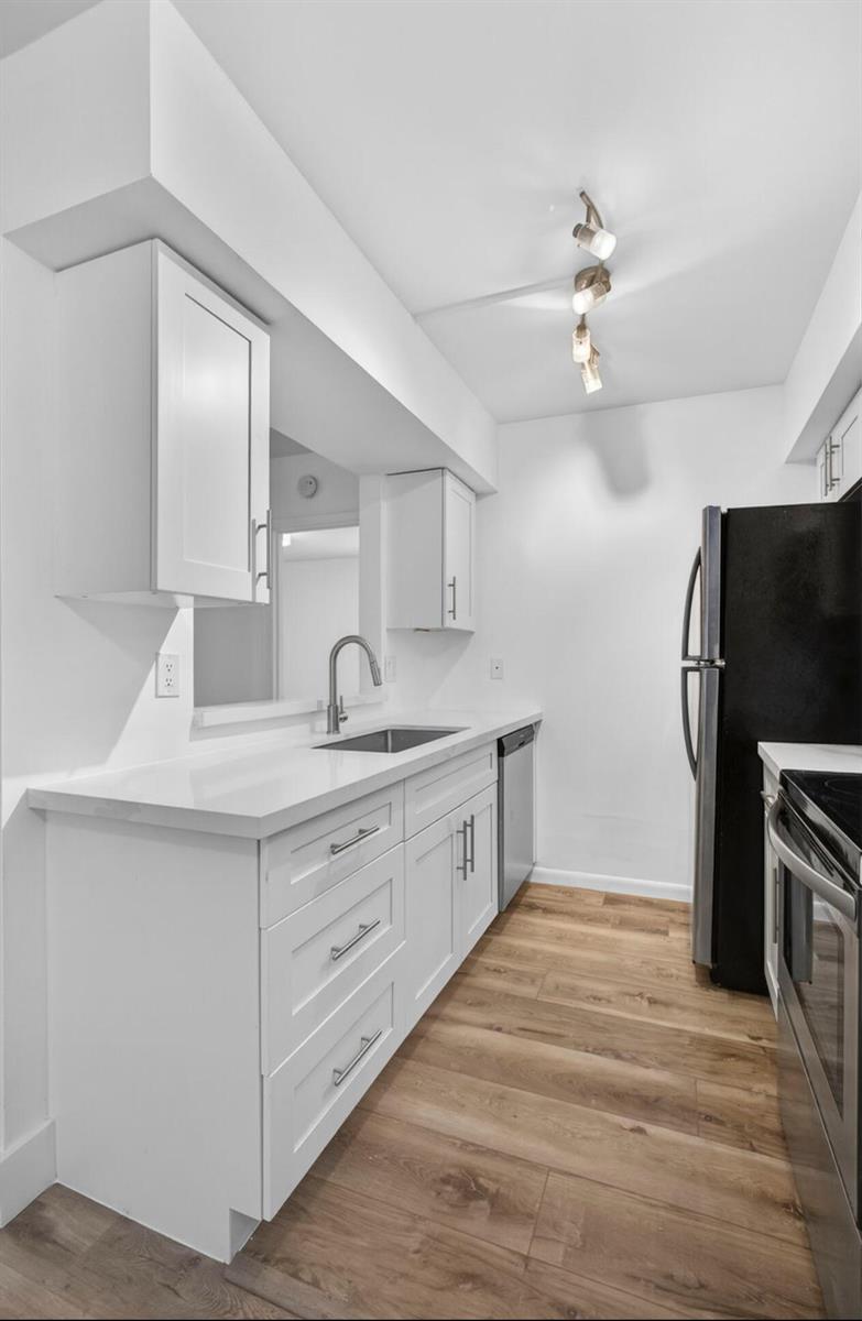 A modern kitchen features white cabinets, light countertops, stainless steel appliances, and wood-look flooring — 6258 Chasewood Drive # C, Jupiter FL 33458, JUPITER, FL