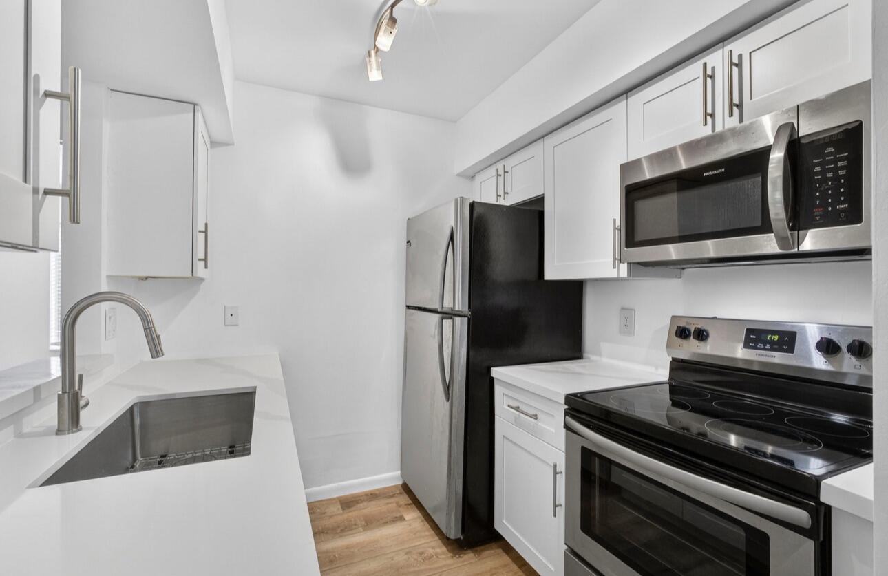 A modern kitchen featuring white cabinets, stainless steel appliances, and white countertops — 6258 Chasewood Drive # C, Jupiter FL 33458, JUPITER, FL