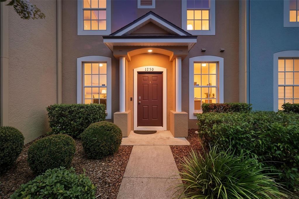 A brown front door with the number 1250 sits under a covered entryway with columns — 1250 CHARLESWORTH DRIVE, WESLEY CHAPEL, FL