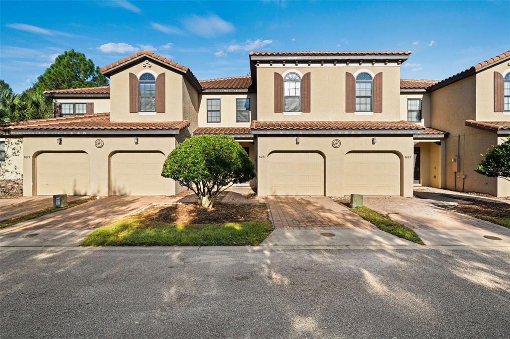 A row of two-story townhouses with beige stucco walls, tile roofs, and attached garages — 8091 BROOKSVILLE DRIVE, DAVENPORT, FL