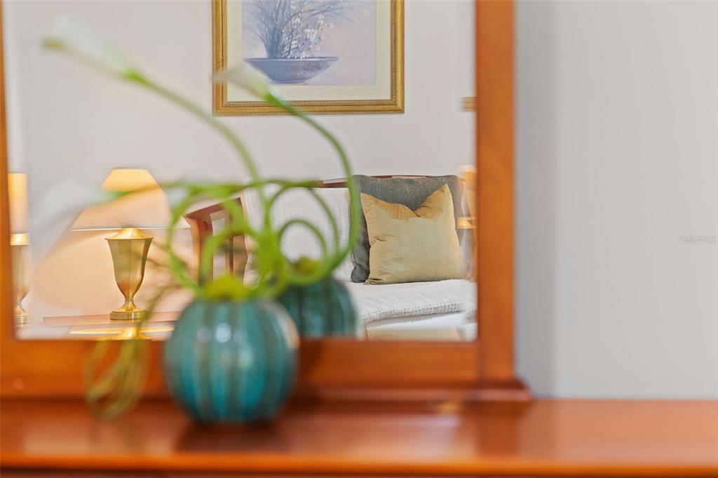 A teal vase sits on a wooden surface in front of a mirror reflecting a bedroom — 8091 BROOKSVILLE DRIVE, DAVENPORT, FL