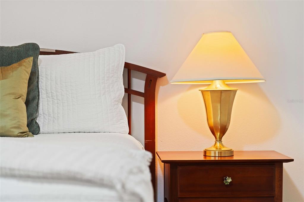 A bedside table with a brass lamp sits next to a bed with white bedding — 8091 BROOKSVILLE DRIVE, DAVENPORT, FL