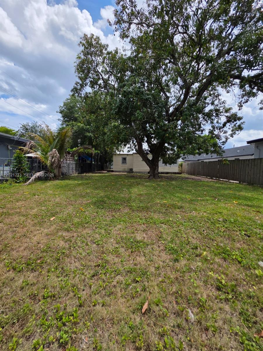 A large backyard features a mature tree, a small house, and a wooden fence — 315 NW 53rd St # 0, Miami FL 33127, MIAMI, FL