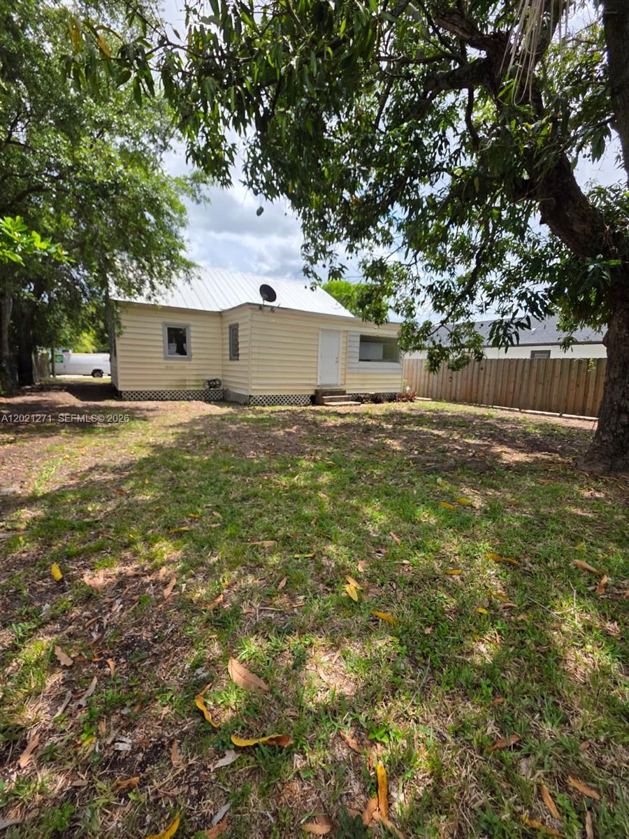 The exterior of a light yellow, single-story house with a metal roof and yard — 315 NW 53rd St # 0, Miami FL 33127, MIAMI, FL