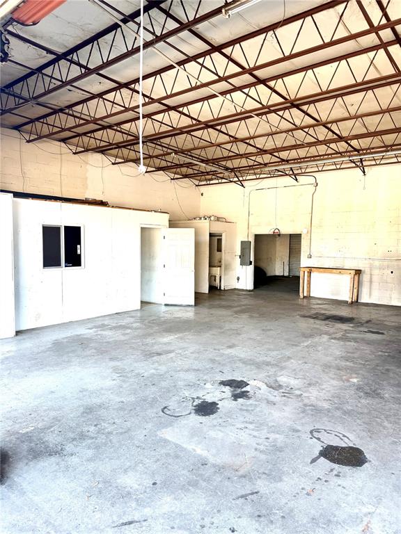 An interior view of a large, open industrial warehouse space with exposed ceiling trusses — 1302 NW 10TH STREET, OCALA, FL