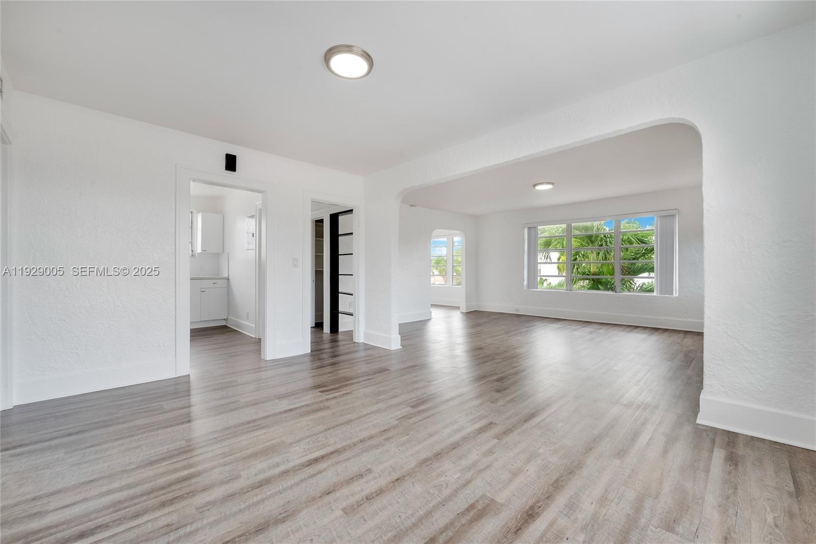 An empty room with white walls, wood-look flooring, and an arched entryway to another space — 1736 SW 9th St # 1738, Miami FL 33135, MIAMI, FL