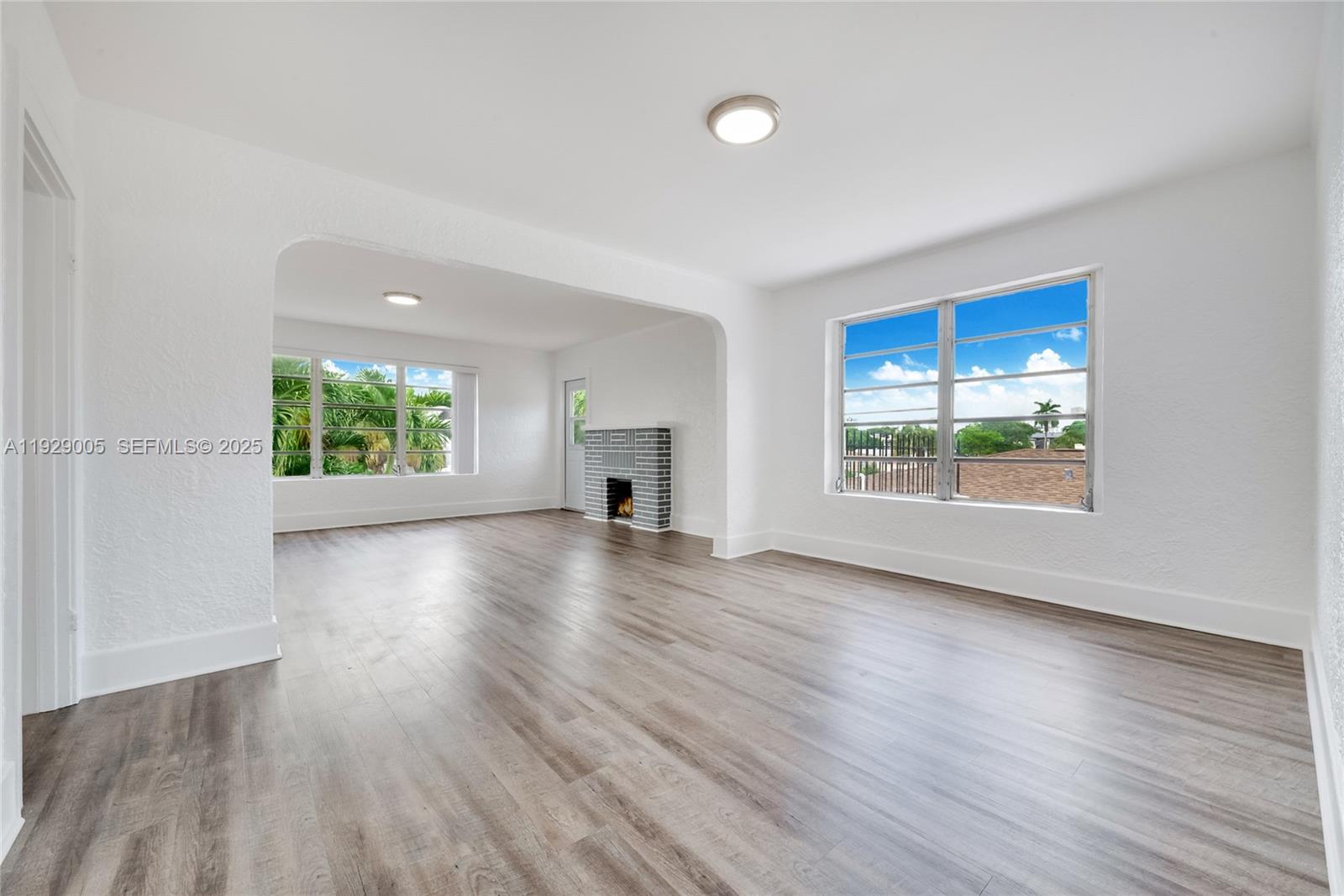 An empty living room features white walls, wood-look flooring, and a gray brick fireplace — 1736 SW 9th St # 1738, Miami FL 33135, MIAMI, FL