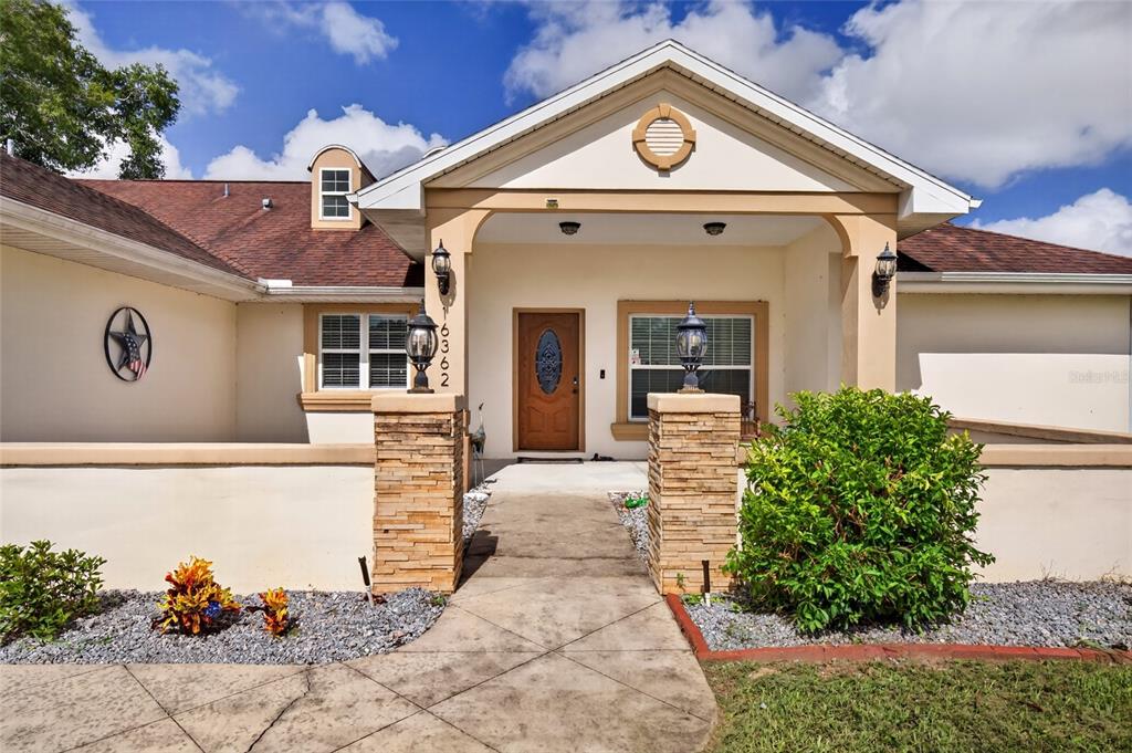 The exterior of a single-story house features a covered entryway with stone-clad pillars — 16362 SE 81ST TERRACE, SUMMERFIELD, FL